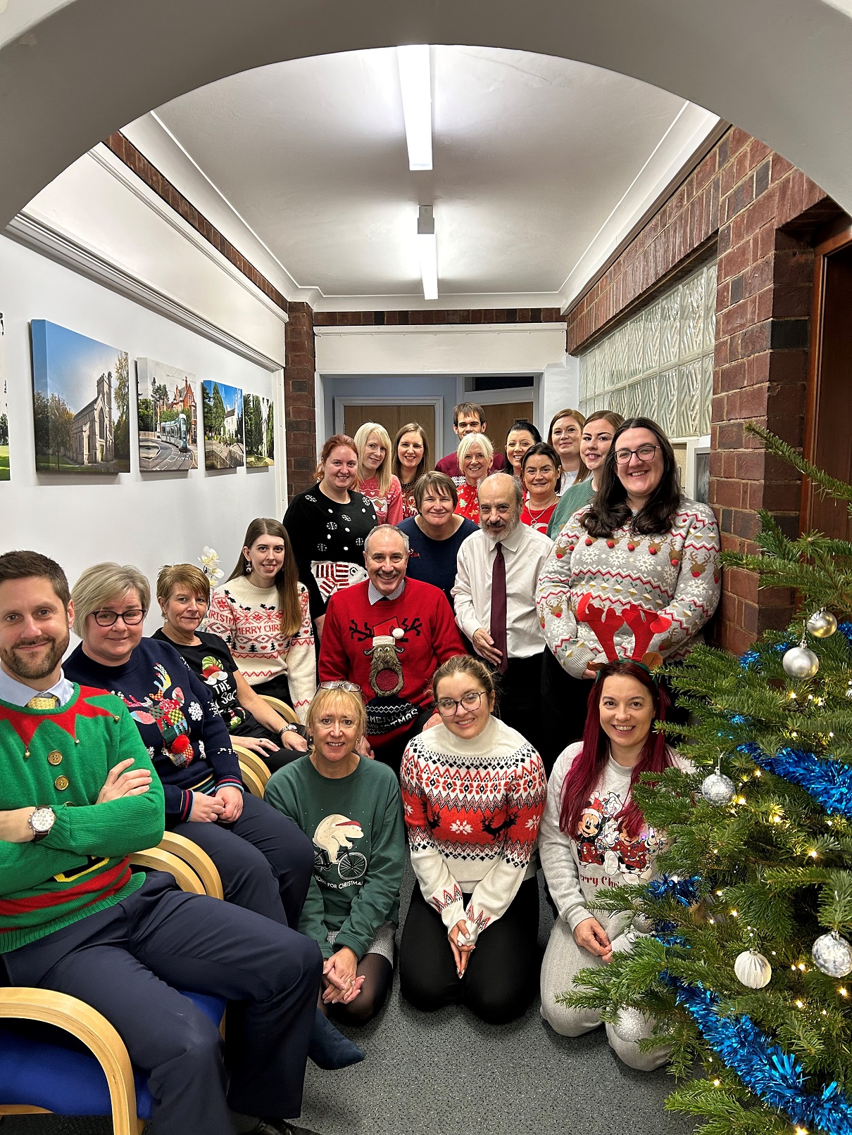 Group photo of Ellis Fermor and Negus staff in Christmas jumpers by a Christmas tree