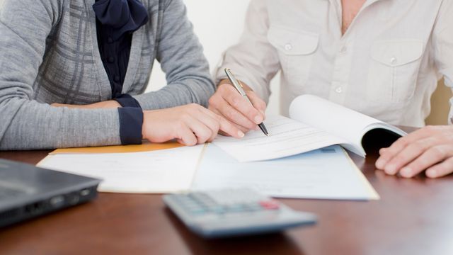 Two professional women signing paperwork at a desk